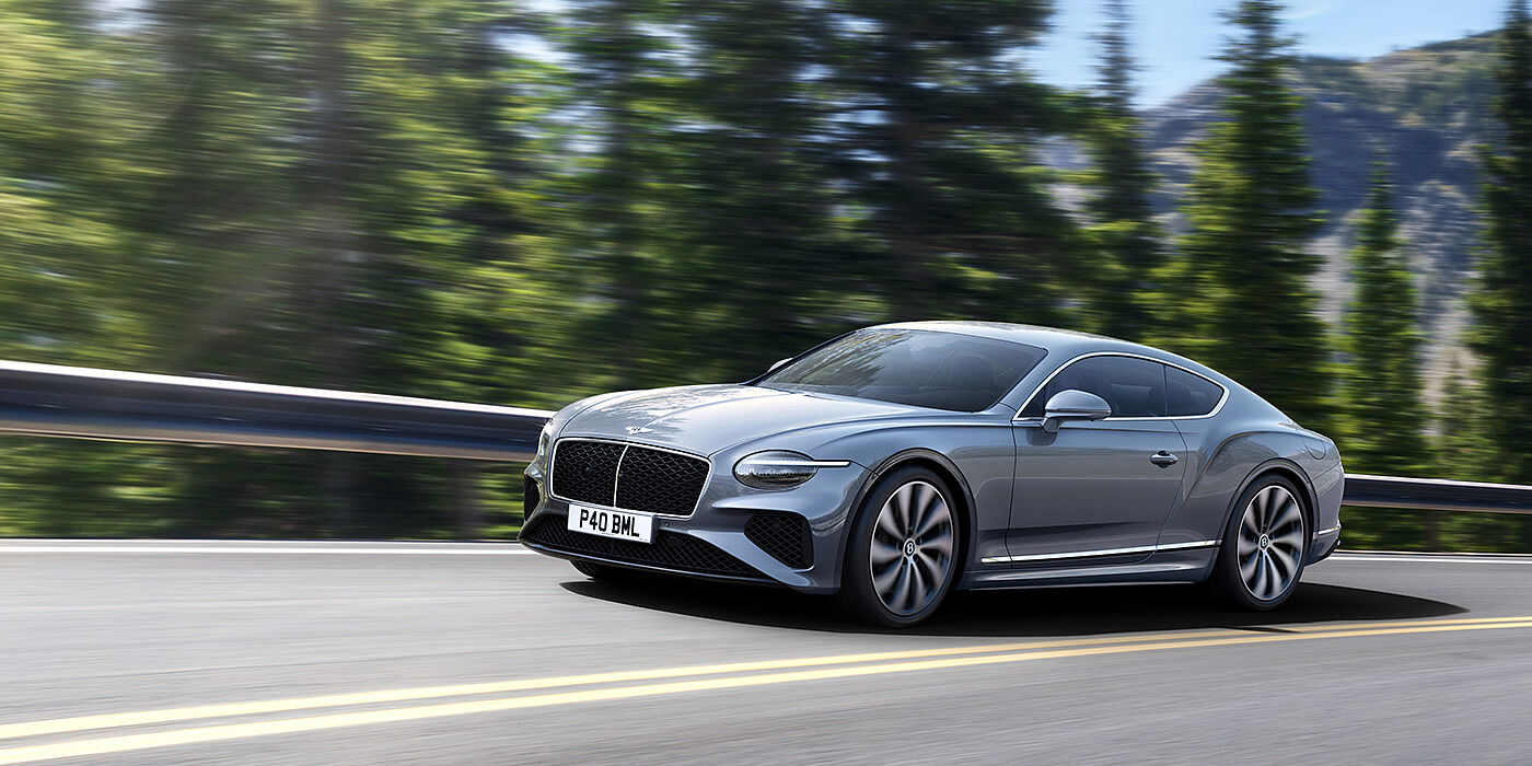 Bentley Manila New Bentley Continental GT coupe in Silverlake paint and 22 inch ten-spoke wheels, driving dynamically on a tree-lined road in the sunshine