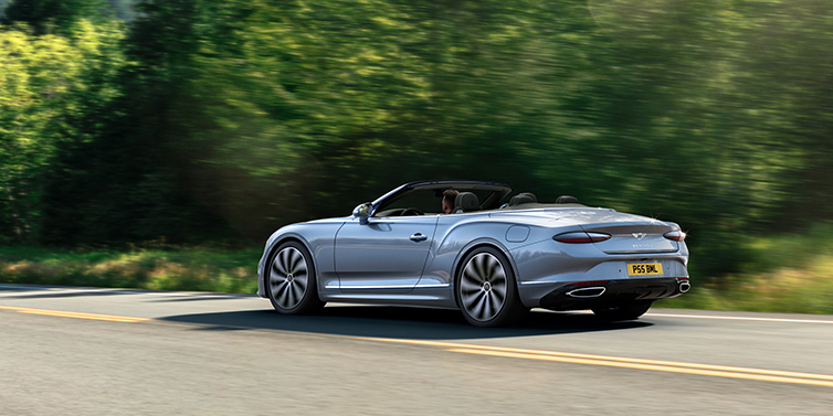 Bentley Manila New Bentley Continental GTC convertible side view in Silverlake paint with 22 inch ten spoke wheels driving dynamically on a country road
