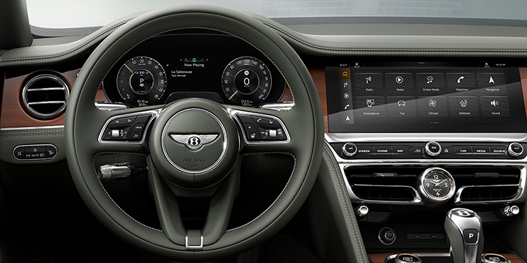 Bentley Manila New Bentley Flying Spur front cabin interior in Cumbrian green hide with Crown Cut walnut veneer showing steering wheel and driver controls